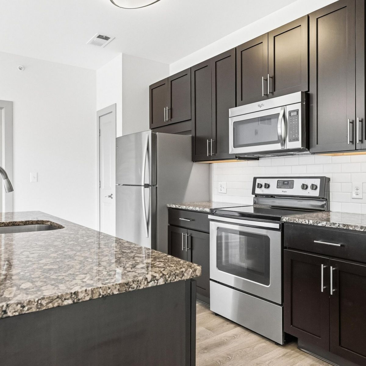 Kitchen with dark brown cabinets, granite countertops, and stainless steel appliances.